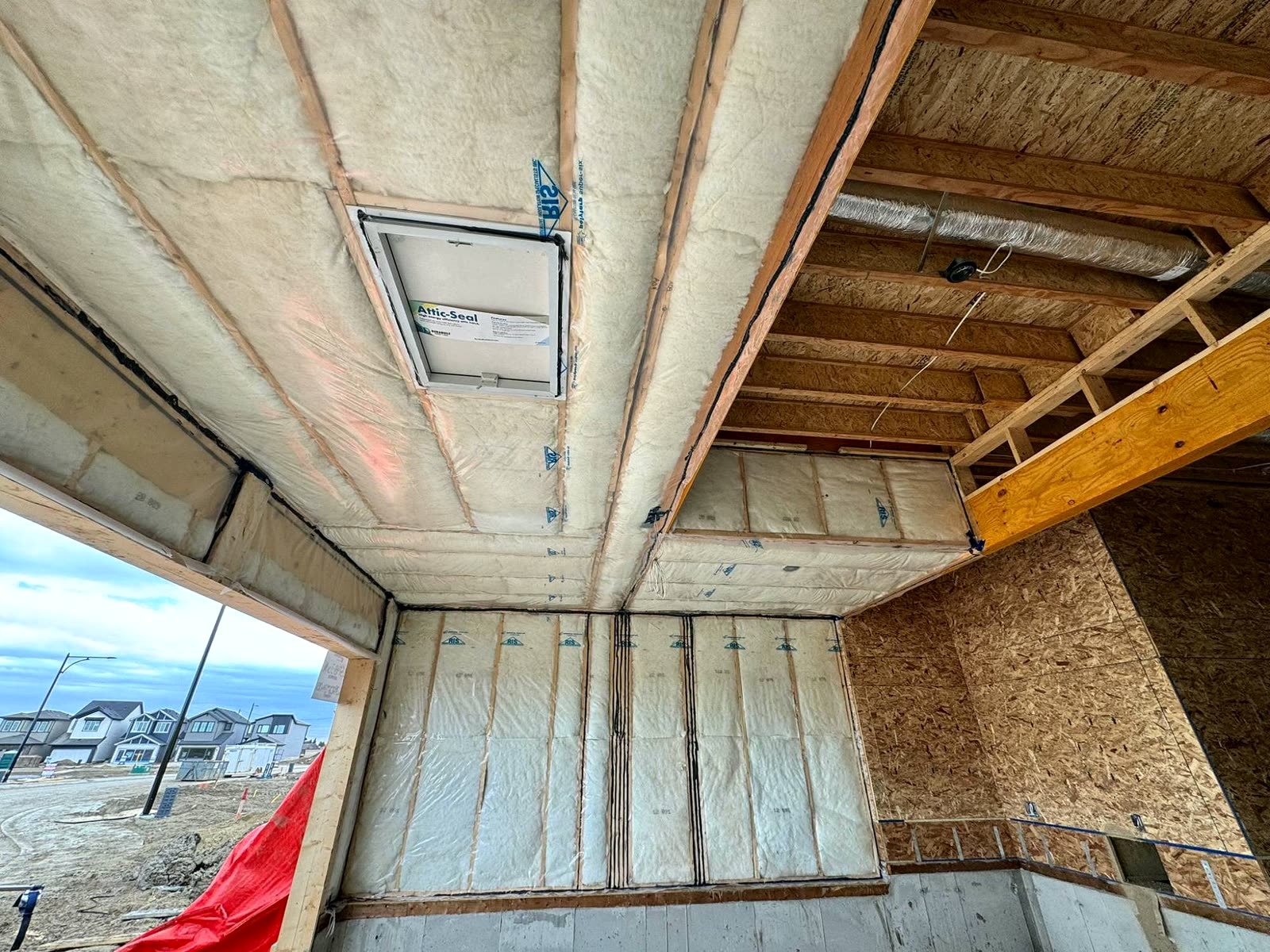Insulated garage ceiling with a sealed attic hatch, new homes visible outside